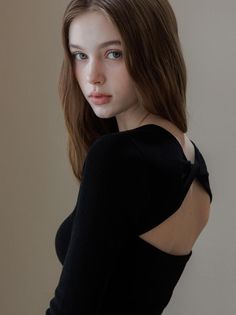 Woman with long hair wearing a black top with an open back