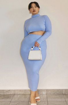 Woman in a light blue ribbed knit cropped top and midi skirt holding a white handbag