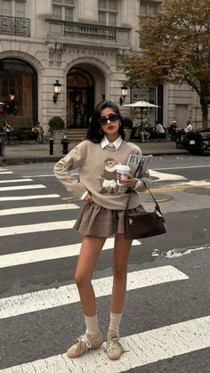 Woman in a plaid skirt and sweater standing on a street crossing