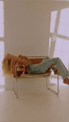 Blonde woman in blue jeans reclining on a chair with exposed skin