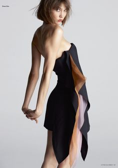 Woman in a black strapless dress with sheer fabric details, looking over her shoulder