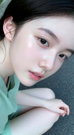 Woman with black hair and glowing skin in a green shirt