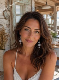 Woman with long wavy hair and green eyes wearing a white top outdoors