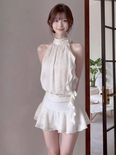 Woman in a white halter neck dress with ruffle details and polka dots indoors