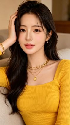 Woman with long dark hair wearing a yellow top and gold jewelry
