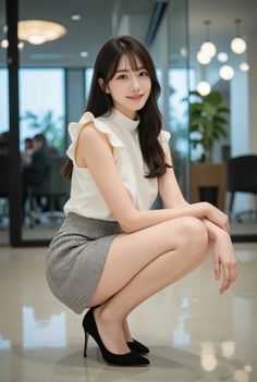 Woman with long hair in a white top and mini skirt squatting in an office