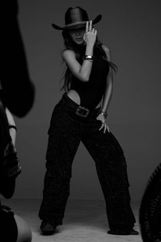 Woman in a cowboy hat and sparkly pants posing in a studio