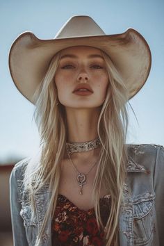 Woman with blonde hair and a cowboy hat wearing a denim jacket outdoors