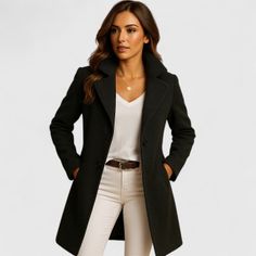 Woman in a black coat, white v-neck shirt, and white pants with a brown belt