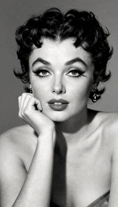 Black and white portrait of a woman with short curly hair and dramatic makeup