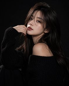 Woman with long dark hair wearing an off-the-shoulder black sweater