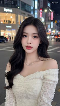 Woman with long dark hair wearing an off-shoulder top in a city at night