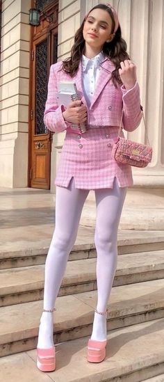Woman in a pink tweed jacket and mini skirt with white tights and platform heels