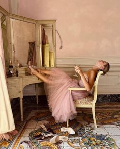 Woman in a pink dress relaxing on a chair with her feet on a dressing table