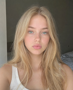 Young woman with blonde hair and blue eyes in a white tank top