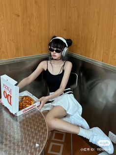 Woman with space buns and sunglasses holding a pizza box indoors