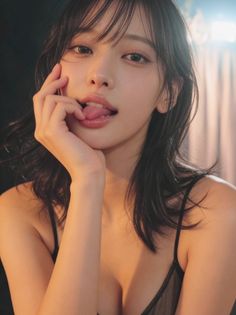 Woman with black hair in lingerie, sticking out her tongue in a provocative pose
