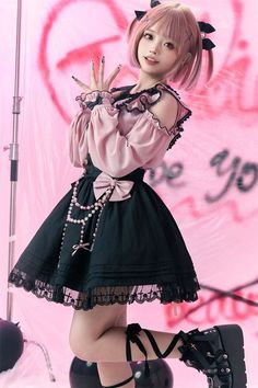 Woman in a pink blouse and black lolita skirt with platform boots on a pink background