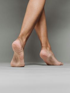 Bare legs and feet crossed against a grey background