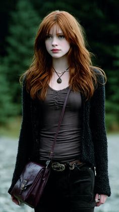 Woman with long red hair and freckles wearing dark clothing and a shoulder bag outdoors