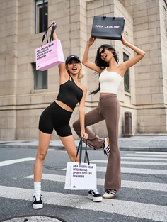 Two women in athletic wear holding shopping bags on a city street