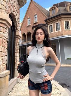 Woman with long dark hair wearing a halter top and denim shorts on a city street