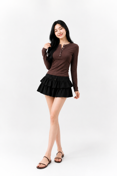 Woman with long black hair wearing a brown shirt and black tiered skirt