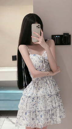 Woman in a white and blue floral ruffle dress taking a mirror selfie