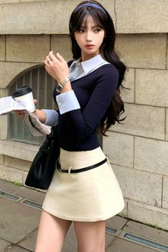 Woman with long dark hair and a headband holding a coffee cup on a street