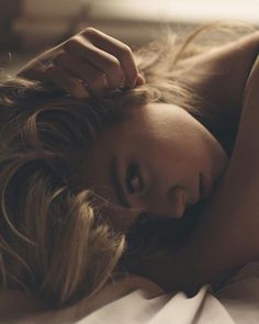 Woman with blonde hair lying down, with soft lighting and dark tones