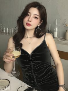 Woman in a black dress holding a glass of wine at a table