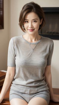 Woman with short hair wearing a sheer gray top indoors