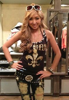 Woman with long blonde hair and sunglasses on her head, wearing a tank top and ripped jeans