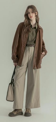 Woman in a brown leather jacket and khaki pants holding a bag