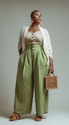 Woman in green wide-leg pants and a white cardigan holding a rattan bag