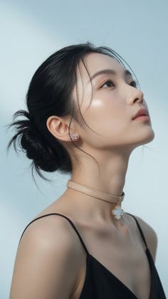 Woman with black hair in an updo wearing a choker and looking up