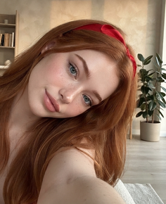 Woman with red hair and a red headband looking at the camera