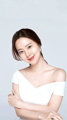 Woman in a white off-shoulder dress smiling against a white background