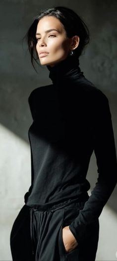 Woman in a black turtleneck with dramatic lighting on her face