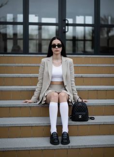 Woman in a blazer and mini skirt sitting on outdoor stairs