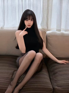 Woman with long black hair sitting on a couch in a black top and mini skirt