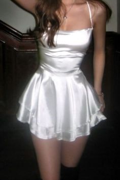 Woman in a white satin mini dress with spaghetti straps indoors