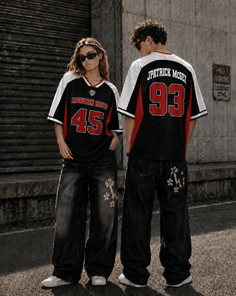 Two people in oversized jerseys and baggy jeans standing on a street
