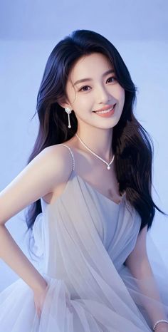 Woman with long dark hair wearing a light blue dress and pearl jewelry