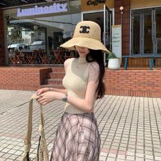 Woman in a straw hat and plaid skirt standing on a street
