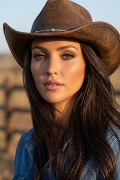 Woman in a cowboy hat and denim jacket outdoors during golden hour