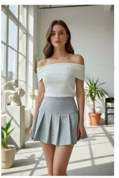 Woman in a white off-shoulder top and grey pleated skirt indoors