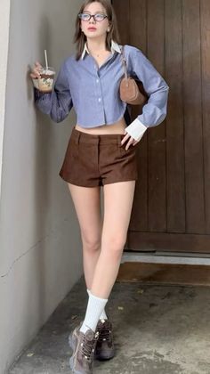 Woman in a striped shirt and brown shorts holding a drink