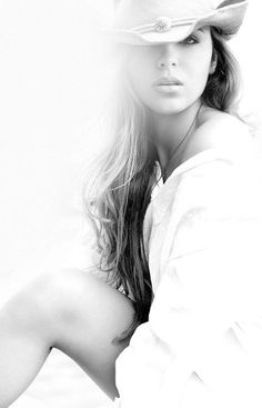 Woman in a cowboy hat and white shirt with exposed shoulder and leg