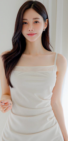 Woman with long dark hair wearing a white dress indoors with soft lighting